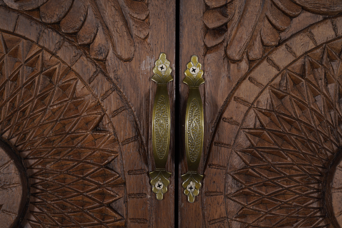 Sienna armoire, close-up of antique-brass door pulls on carved mango wood
